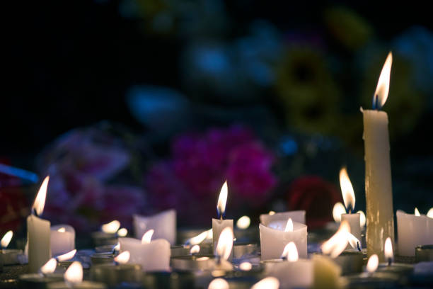 istock A makeshift memorial vigil with various size candles and flowers at night 857856780