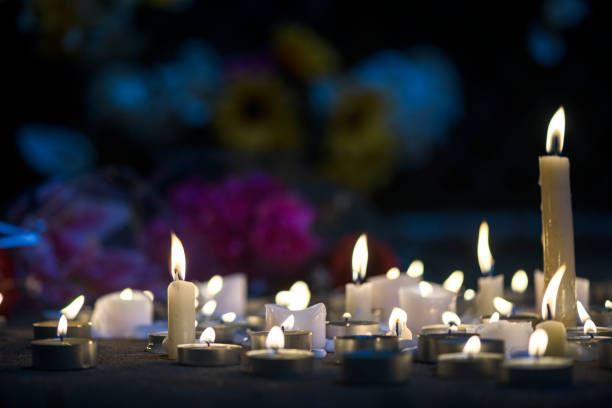 A makeshift memorial vigil with various size candles and flowers at night stock photo
