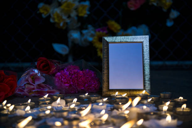 A makeshift memorial vigil with picture frame, various size candles and flowers at night