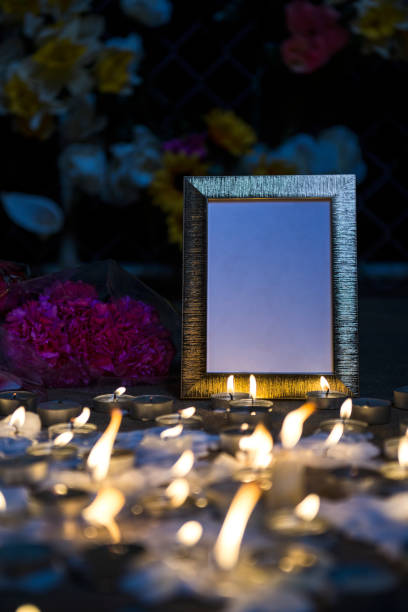 istock A makeshift memorial vigil with picture frame, various size candles and flowers at night 857857728