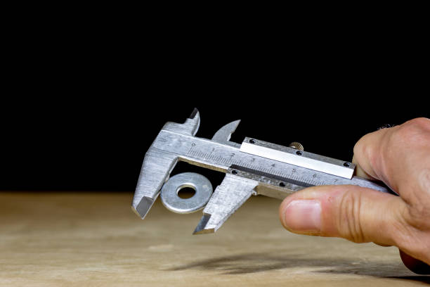 istock Old good caliper in hand while measuring the abdomen. Wooden table, black background 857866274