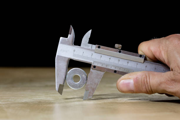 istock Old good caliper in hand while measuring the abdomen. Wooden table, black background 857868858