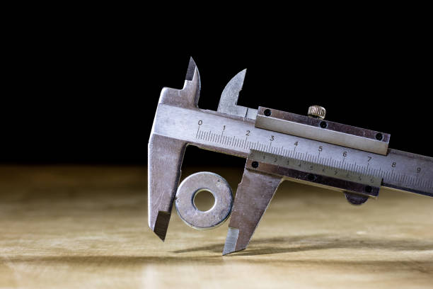 istock Old good caliper in hand while measuring the abdomen. Wooden table, black background 857869280