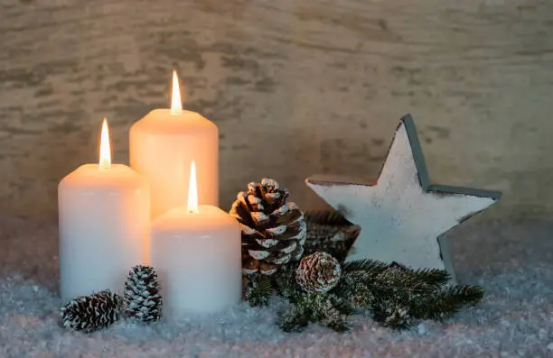 White Christmas candles at snow with traditional decoration.