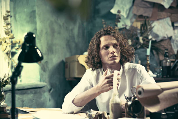 istock Writer at work. Handsome young writer sitting at the table and writing something in his sketchpad 857881614