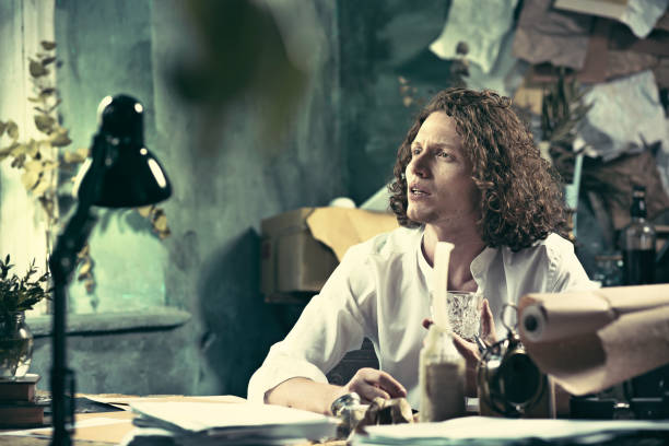 istock Writer at work. Handsome young writer sitting at the table and writing something in his sketchpad 857881702