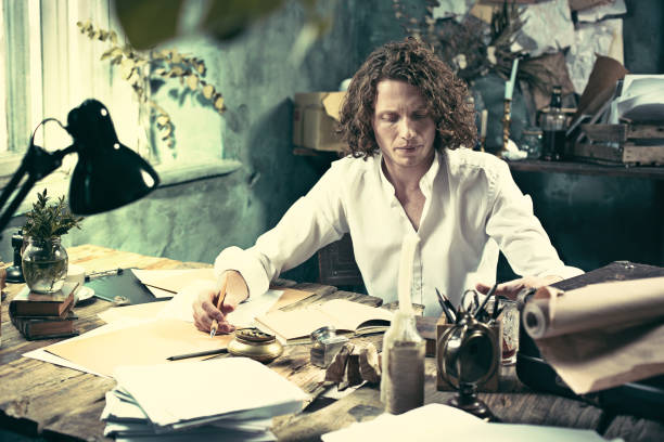 istock Writer at work. Handsome young writer sitting at the table and writing something in his sketchpad 857881766