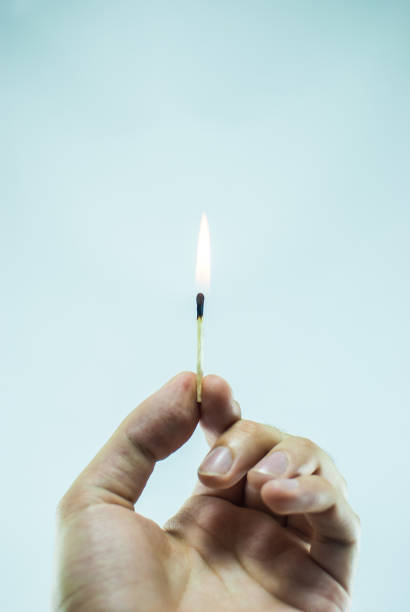 istock Man's hand holding a lighted match in the fingers 857884778