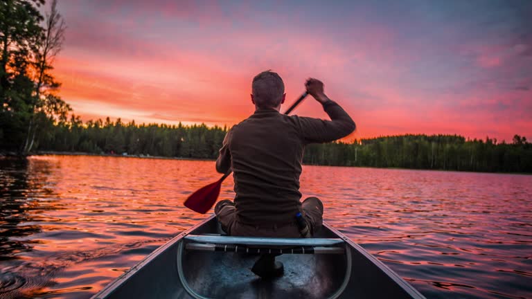 Man paddling a canoe at sunset - POV