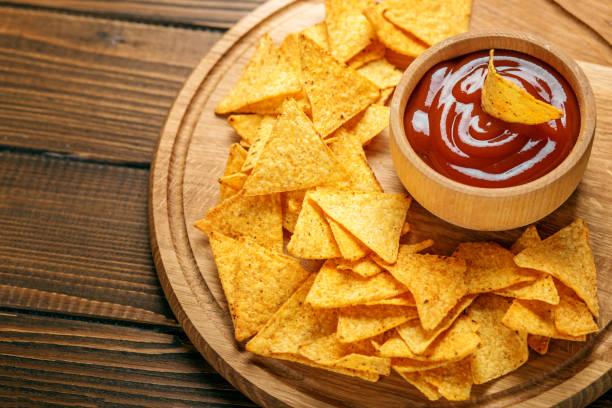 istock Flat lay. Mexican nachos chips with a sharp tomato sauce on the tray. Concept - bad food, cafe, pub, party. 857889080