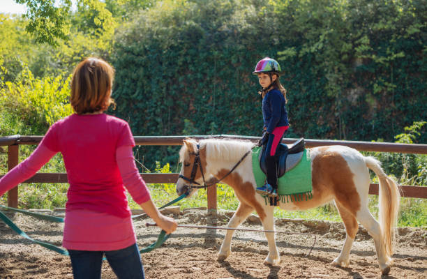 personal trainer in horseback riding school for kids teaching trot - teaching child horseback riding horse imagens e fotografias de stock