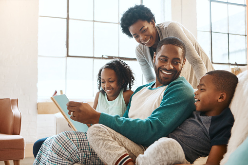 Shot of a family reading a book indoors