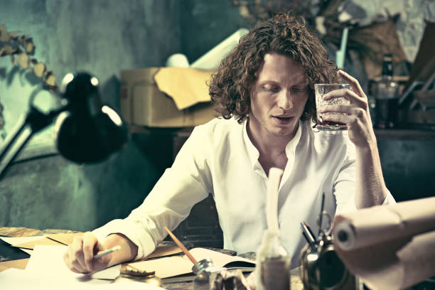 Writer at work. Handsome young writer sitting at the table and writing something in his sketchpad