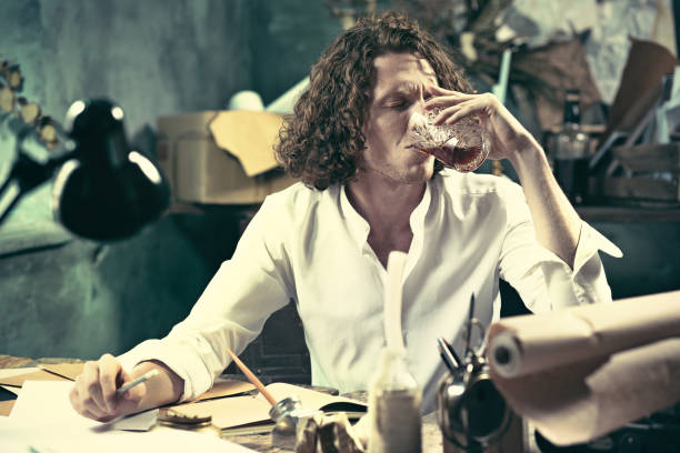 istock Writer at work. Handsome young writer sitting at the table and writing something in his sketchpad 857897374