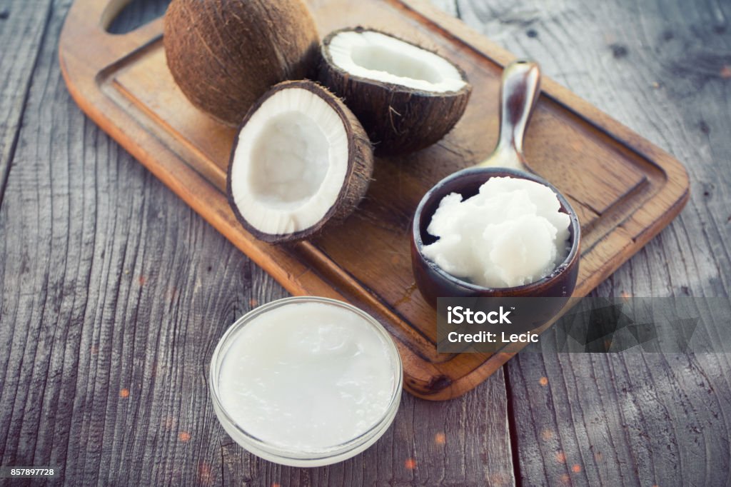 Coconut with coconut oil in jar on wooden background Coconut Oil Stock Photo