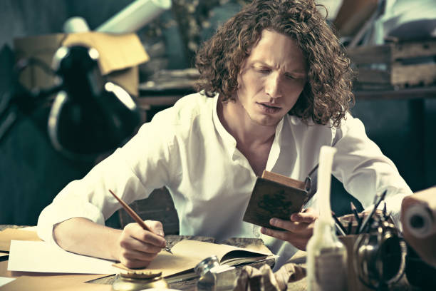 istock Writer at work. Handsome young writer sitting at the table and writing something in his sketchpad 857901314
