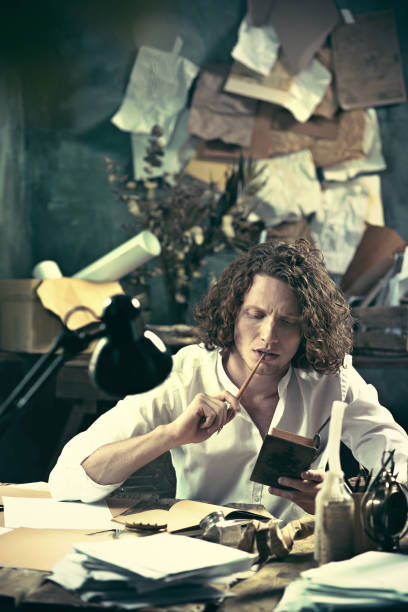 istock Writer at work. Handsome young writer sitting at the table and writing something in his sketchpad 857902238