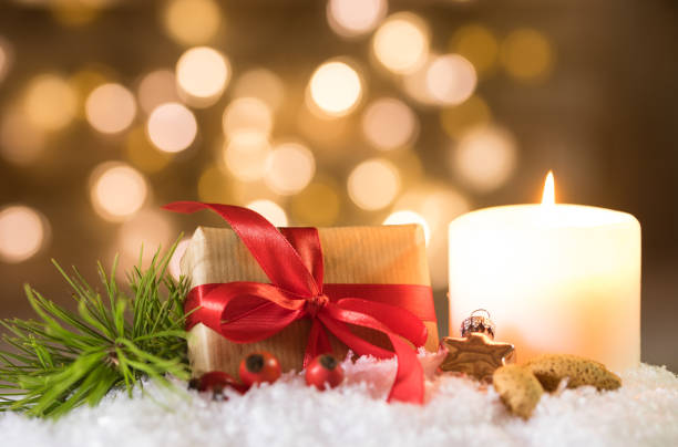 istock Christmas gift with candle on snow and sparkling lights background 857908766