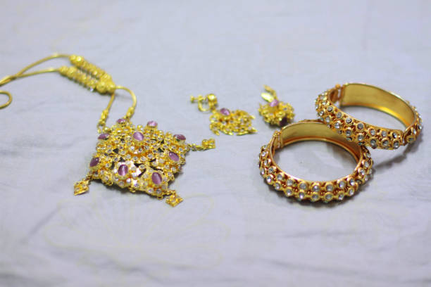 istock Close up shiny gold jewelery on white fabric 857916230