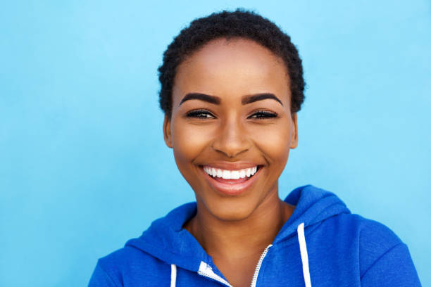 istock Close up smiling young black woman against blue background 857924430