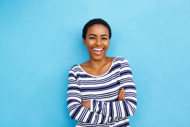 feliz joven mujer negra riendo contra pared azul - one young woman only women people 20s fotografías e imágenes de stock