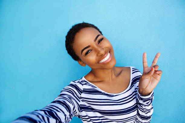 istock cool young black woman taking selfie with peace hand sign 857924534