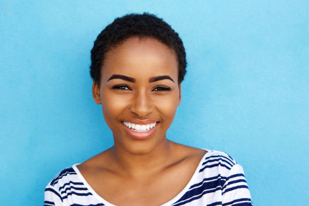 istock happy young black woman smiling against blue background 857924556