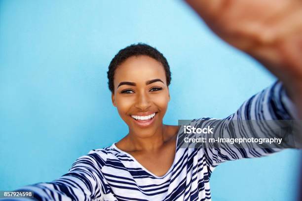 Photo libre de droit de Sourire Femme Afroaméricaine Prenant Selfie Contre Mur Bleu banque d'images et plus d'images libres de droit de Selfie