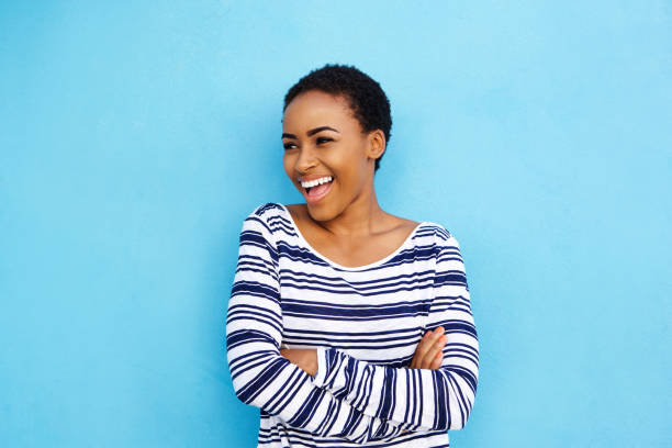 cool young black woman laughing against blue wall