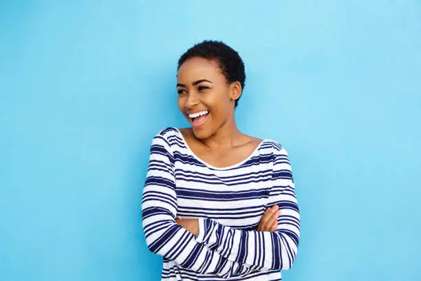 Photo of cool young black woman laughing against blue wall