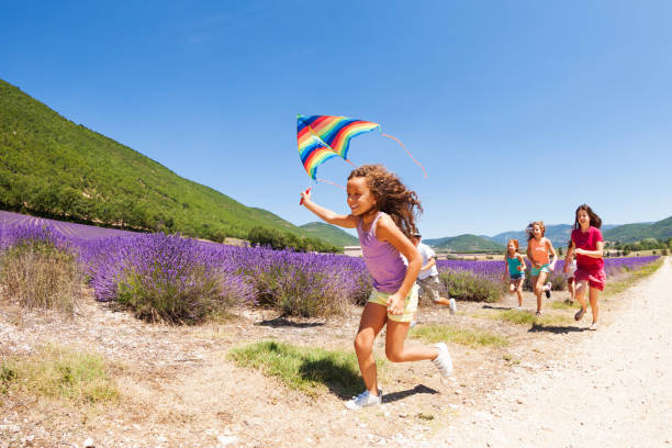 Cute girl running with kite through lavender field Exited preteen girl running with rainbow kite through lavender meadow girls playing stock pictures, royalty-free photos & images