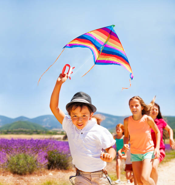 istock Happy boy flying rainbow kite with his friends 857925198