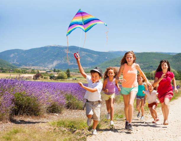 istock Excited boy flying rainbow kite with his friends 857926222