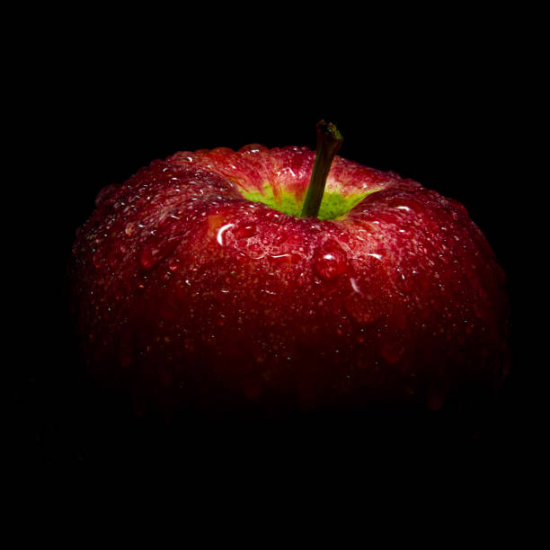 istock Water droplet on glossy surface of red apple on black background 857932720