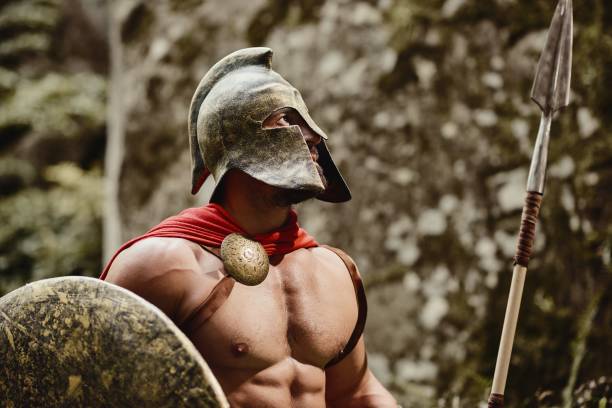 Strong Roman warrior on nature Portrait of anonymous muscular man wearing outfit of ancient gladiator posing in helmet with shield and spear in hands looking away. Spartan. armory photos stock pictures, royalty-free photos & images