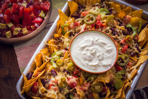 Baked Nachos Tortilla Chips with Salsa, Minced Meat and Jalapenos Baked Nachos Tortilla Chips with Salsa, Minced Meat and Jalapenos served with Sour Cream nacho chip photos stock pictures, royalty-free photos & images