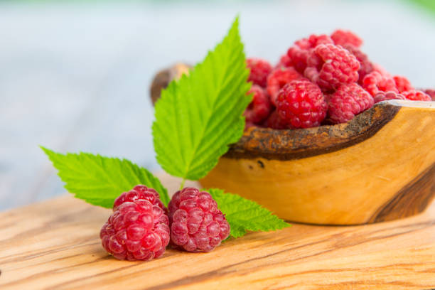 istock Wild raspberry with leaves on wooden background 857947188
