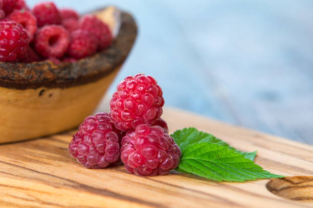 Wild raspberry with leaves on wooden background