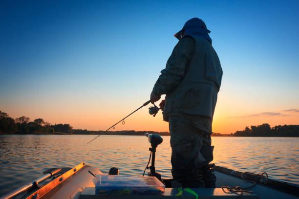 rybak łowiący ryby w jeziorze o zachodzie słońca - bass zdjęcia i obrazy z banku zdjęć
