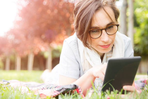 femme à l'aide de tablette numérique - women grass glasses e reader photos et images de collection