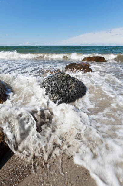 istock sunny day with Waves hitting stones on the beach 857962248