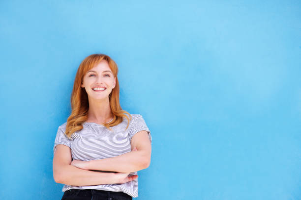istock happy woman standing against blue wall 857963134