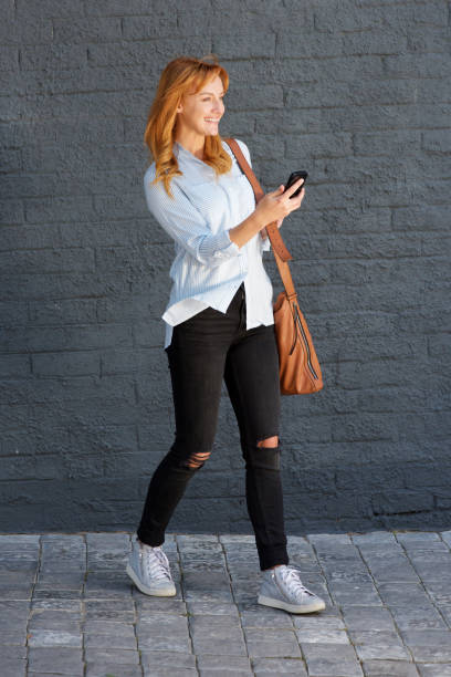 istock cheerful woman walking with mobile phone and bag 857963164
