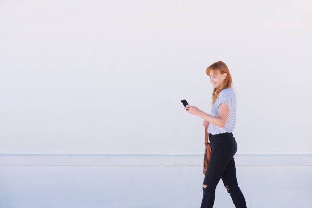 istock beautiful young woman walking with mobile phone 857963294