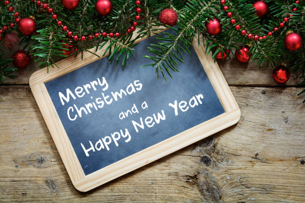 istock Fir tree branches with red christmas balls and a writing  board on rustic wooden planks, sample text Merry Christmas and a Happy New Year 857965680