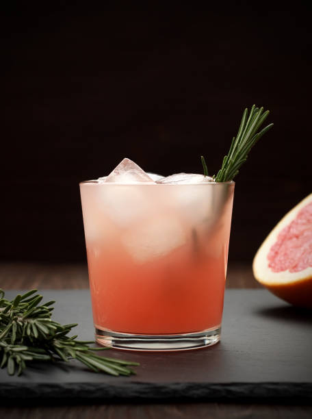 Refreshing grapefruit cocktail with rosemary on dark background. stock photo
