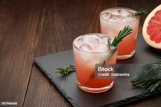 Two Glasses Of Citrus Summer Drink With Grapefruit And Rosemary On Dark Background Stock Photo - Download Image Now