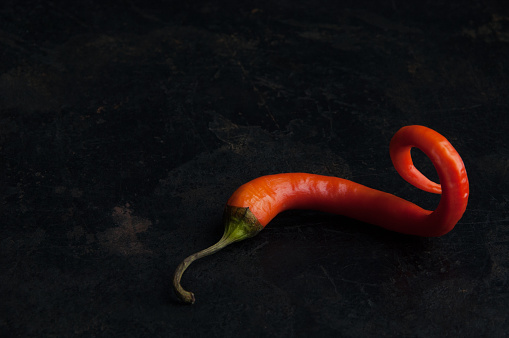 Red pepper on black textured background