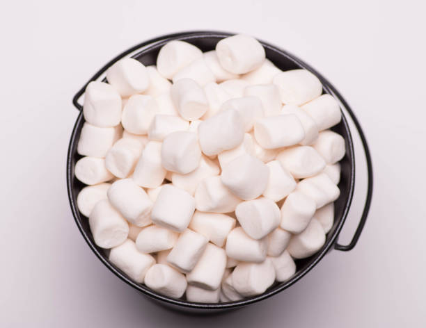 istock White mini marshmallows background close-up texture. A pile of  mini white puffy marshmallows in black bowl isolated on white background. Marshmallow concept. Wallpaper for desktop. Selective focus. Food background. Copy space. 857970084