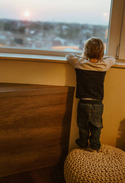 istock back view of young boy looking trough window 857972532